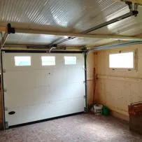 Motore a traino Serrmetall per porta sezionale con guida a soffitto e luce di cortesia.
