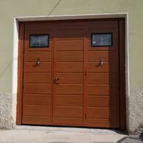 Porta basculante per garage realizzata in pannelli sandwich schiumati, finitura liscia di colore effetto legno con portina