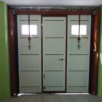 Porta basculante per garage realizzata in pannelli sandwich schiumati, finitura liscia di colore effetto legno con portina interno